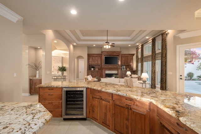 kitchen with crown molding, light stone countertops, beverage cooler, and ceiling fan