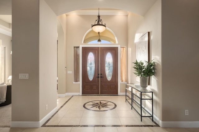 foyer with ornamental molding and light tile patterned floors