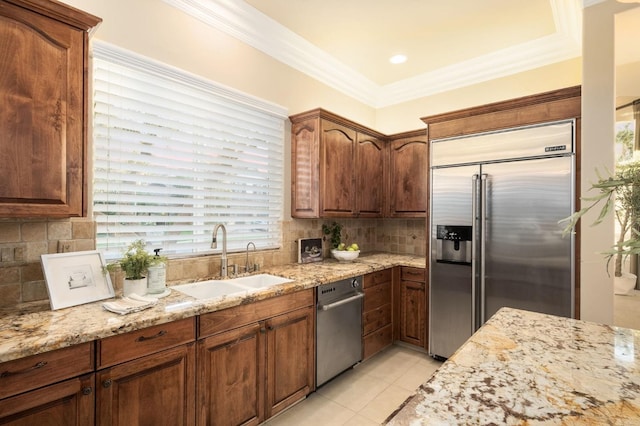 kitchen with a healthy amount of sunlight, sink, light stone countertops, and built in refrigerator