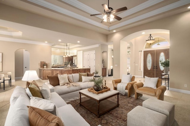 living room with tile patterned floors, crown molding, a tray ceiling, and ceiling fan