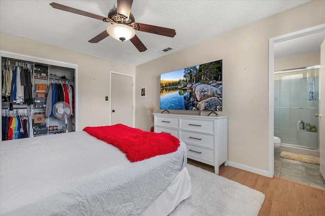 bedroom with connected bathroom, light hardwood / wood-style flooring, ceiling fan, a textured ceiling, and a closet