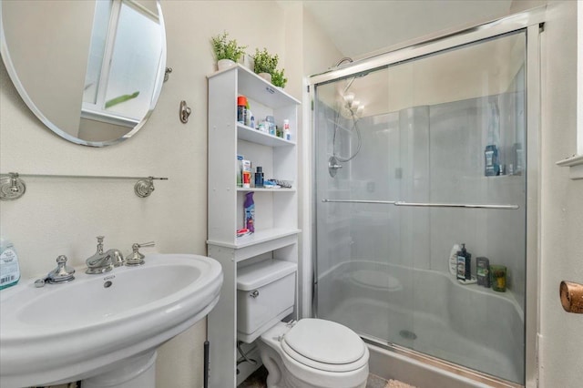 bathroom with toilet, a shower with door, and sink