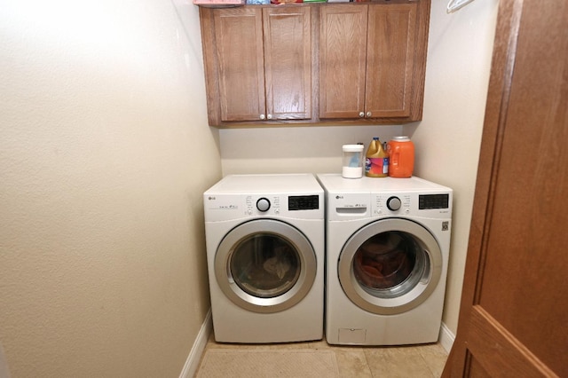 washroom with washer and dryer, cabinet space, baseboards, and light tile patterned floors