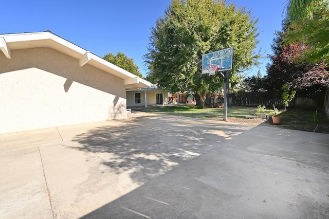 view of property exterior featuring driveway, fence, and stucco siding