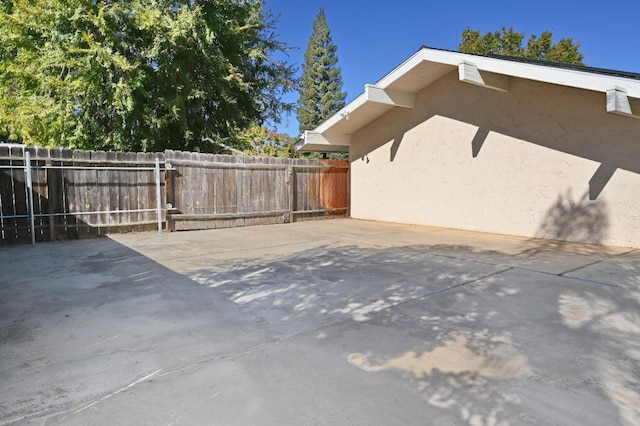 view of side of property with a patio area, fence, and stucco siding