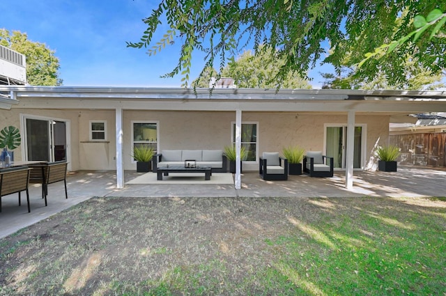 rear view of house with a patio, outdoor lounge area, and stucco siding