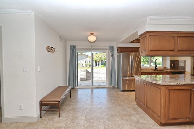 kitchen featuring brown cabinetry, freestanding refrigerator, and a sink