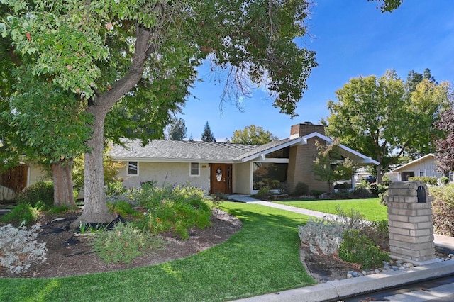 view of front of house featuring a chimney, a front lawn, and stucco siding