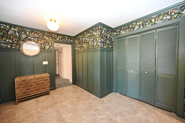 interior space with crown molding, a decorative wall, and wallpapered walls