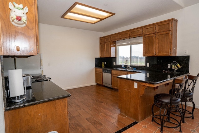 kitchen with a kitchen breakfast bar, dark hardwood / wood-style flooring, decorative backsplash, stainless steel dishwasher, and kitchen peninsula