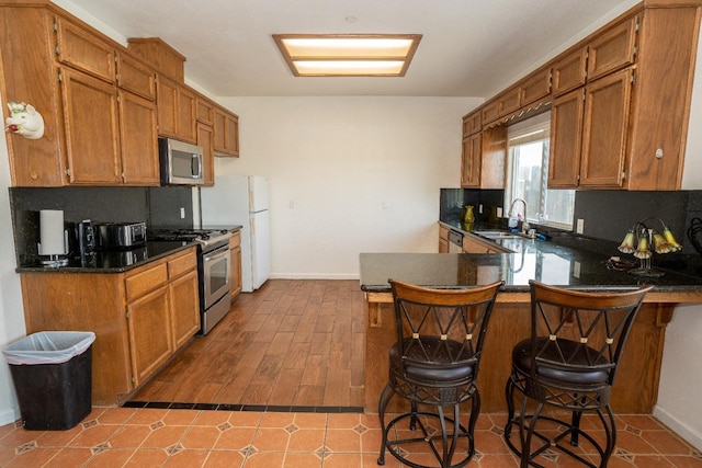 kitchen with appliances with stainless steel finishes, sink, a kitchen bar, and kitchen peninsula