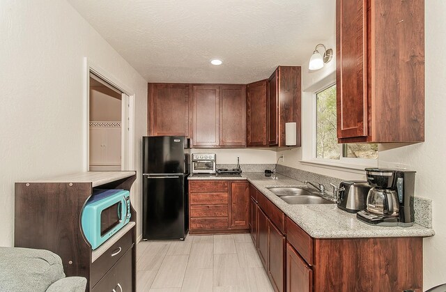 kitchen featuring sink, black refrigerator, and a textured ceiling