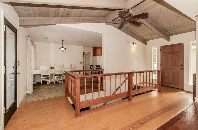 hallway featuring lofted ceiling with beams, light hardwood / wood-style floors, and wooden ceiling