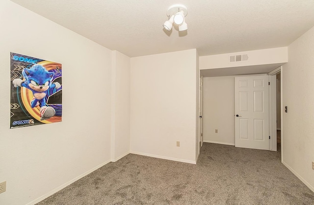 carpeted empty room with a textured ceiling