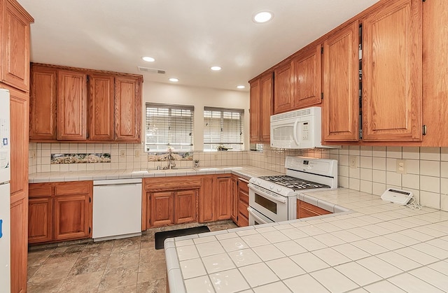 kitchen with sink, tile counters, white appliances, and tasteful backsplash