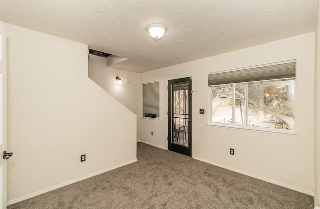 empty room featuring dark carpet and a textured ceiling