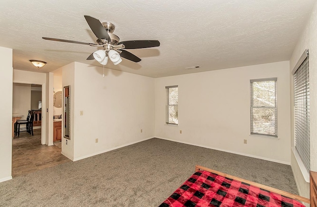 empty room with ceiling fan, carpet, and a textured ceiling