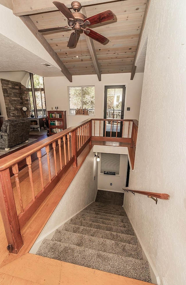 stairway featuring carpet, lofted ceiling with beams, and wooden ceiling