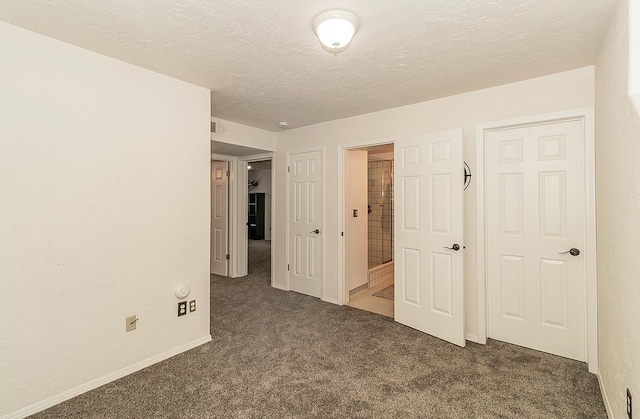 unfurnished bedroom featuring a textured ceiling and dark colored carpet