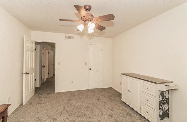 unfurnished bedroom with ceiling fan, carpet flooring, and a textured ceiling