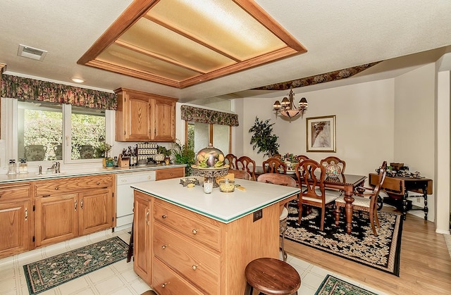 kitchen with white dishwasher, a kitchen island, a textured ceiling, and a chandelier