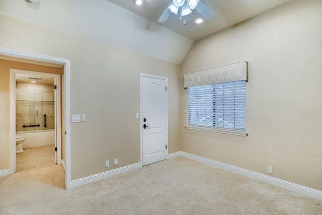 unfurnished bedroom featuring connected bathroom, lofted ceiling, light carpet, and ceiling fan