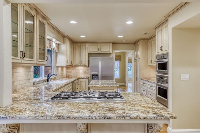 kitchen featuring tasteful backsplash, appliances with stainless steel finishes, sink, kitchen peninsula, and a kitchen breakfast bar