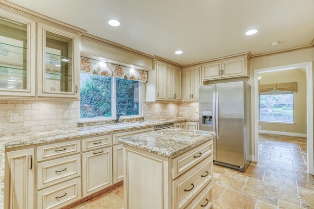 kitchen featuring backsplash, stainless steel fridge, a center island, and cream cabinets