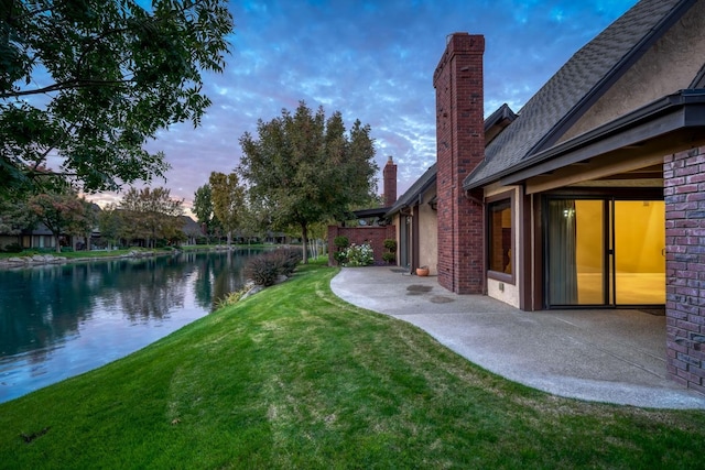 yard at dusk featuring a water view