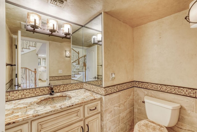 bathroom with toilet, vanity, and tile walls