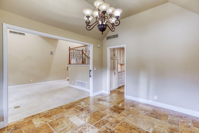 carpeted empty room featuring a chandelier and vaulted ceiling