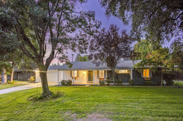 ranch-style home featuring a garage, a yard, and covered porch