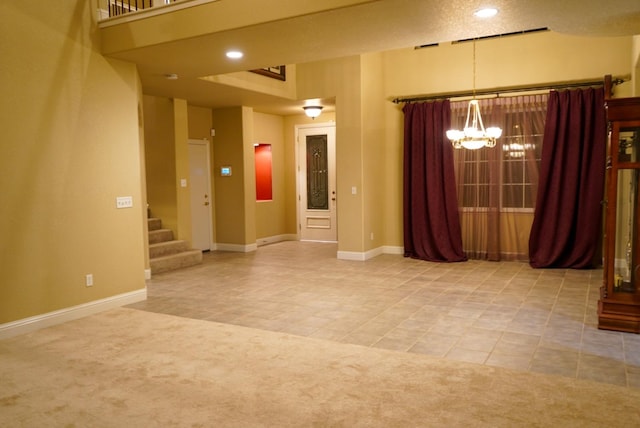 carpeted spare room featuring a chandelier and a textured ceiling