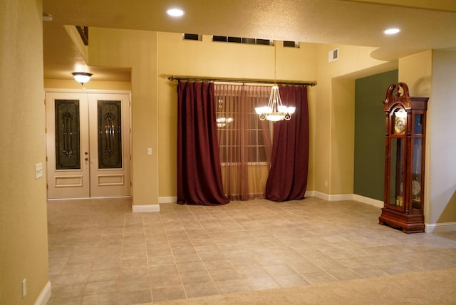 spare room featuring an inviting chandelier and french doors