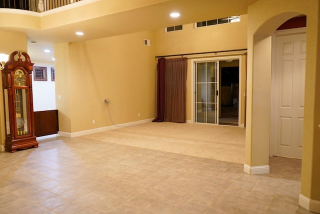 carpeted empty room featuring a high ceiling