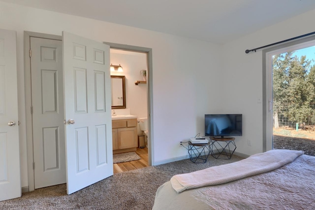 bedroom with ensuite bathroom, sink, and carpet flooring