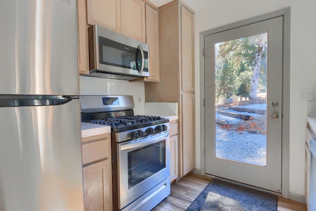 kitchen featuring appliances with stainless steel finishes, light hardwood / wood-style flooring, and light brown cabinets