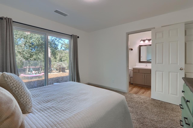 bedroom with ensuite bathroom, sink, and light wood-type flooring