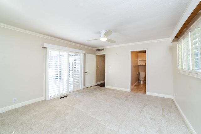 unfurnished bedroom with a closet, light carpet, a walk in closet, crown molding, and ceiling fan