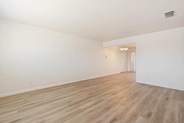 empty room featuring light hardwood / wood-style flooring and a notable chandelier