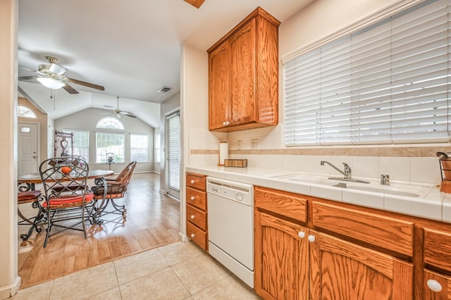 kitchen featuring tile countertops, light wood-type flooring, white dishwasher, and sink