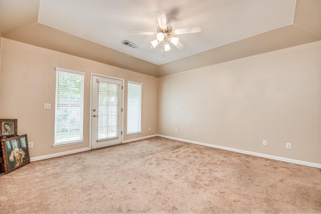 carpeted spare room with a tray ceiling and ceiling fan