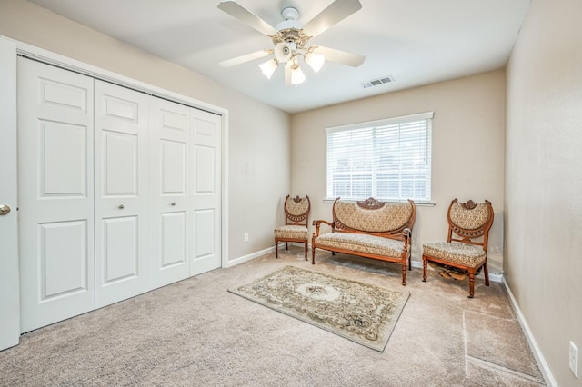 living area featuring light colored carpet and ceiling fan