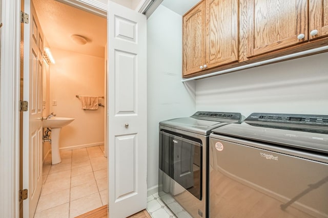 laundry area with washer and dryer, cabinets, light tile patterned floors, and sink