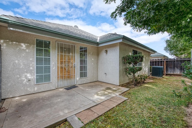 property entrance with a yard, a patio, and central AC unit