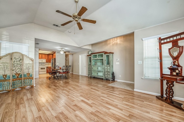 living room with ceiling fan, light hardwood / wood-style flooring, and lofted ceiling