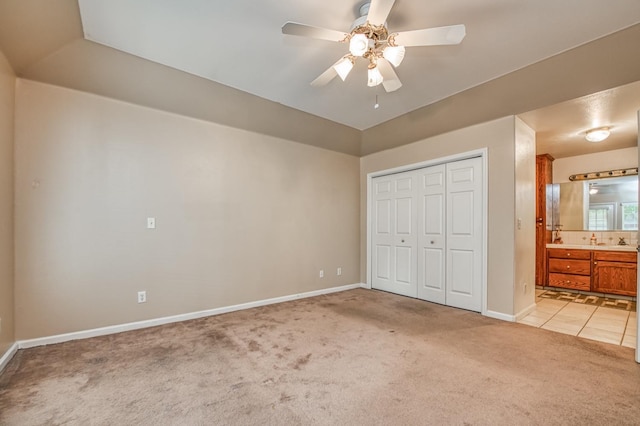 unfurnished bedroom featuring ceiling fan, ensuite bathroom, and light carpet