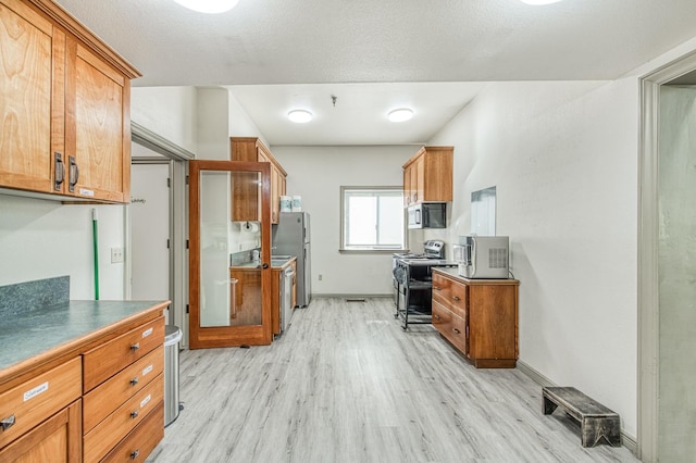 kitchen with stainless steel appliances, a textured ceiling, and light hardwood / wood-style flooring