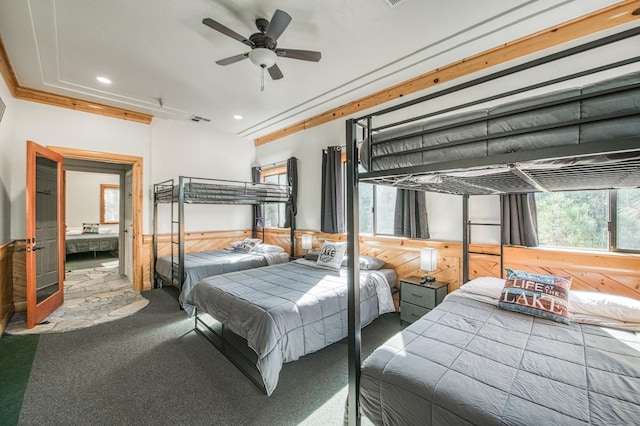 bedroom with carpet flooring, wooden walls, ceiling fan, and crown molding