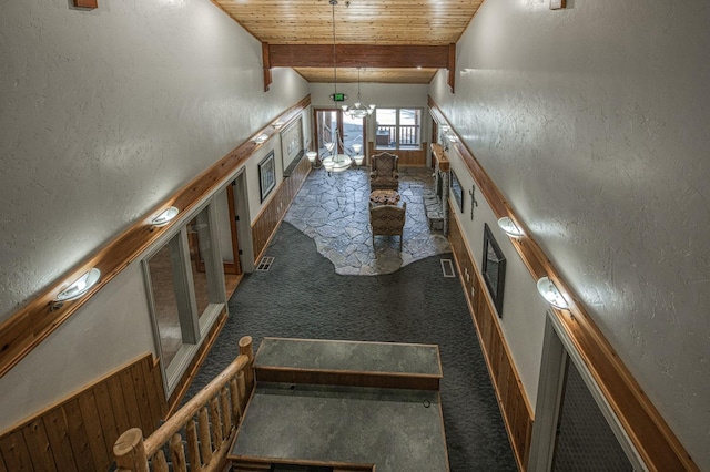 interior space with wood ceiling, carpet flooring, an inviting chandelier, and lofted ceiling with beams